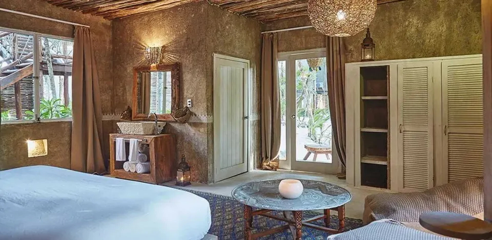 Light-filled guest room with canopy window and seating at Nômade Temple Tulum