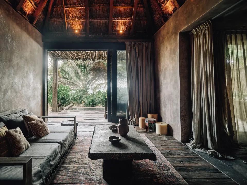Shaded seating area in a lounge with low table and sliding doors to a deck at Nômade Temple Tulum
