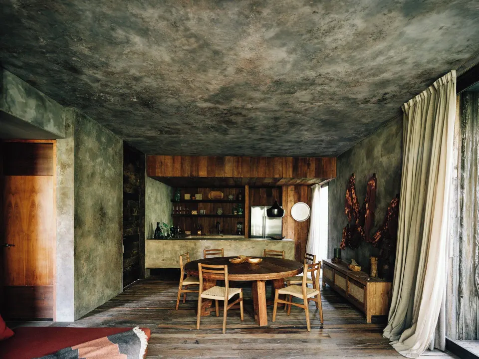 Open-plan dining and kitchen area with round table at Nômade Temple Tulum