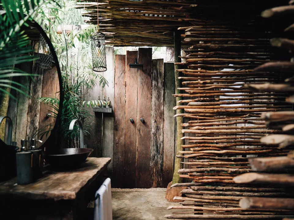 Outdoor rustic shower and wash area surrounded by wood at Nômade Temple Tulum