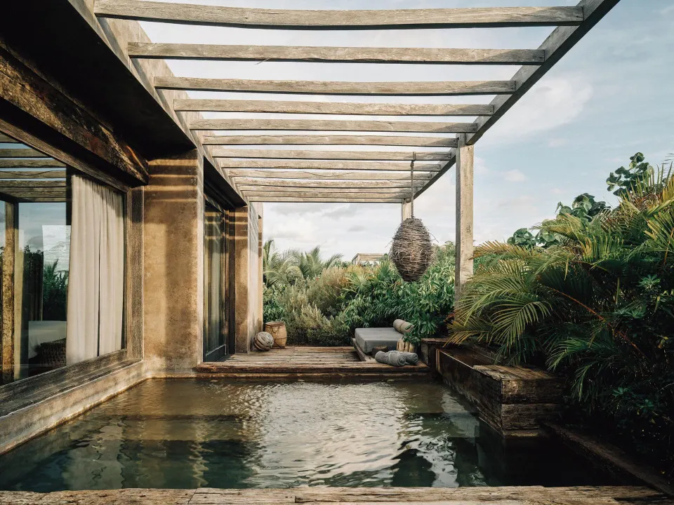 Private plunge pool and shaded deck framed by tropical plants at Nômade Temple Tulum