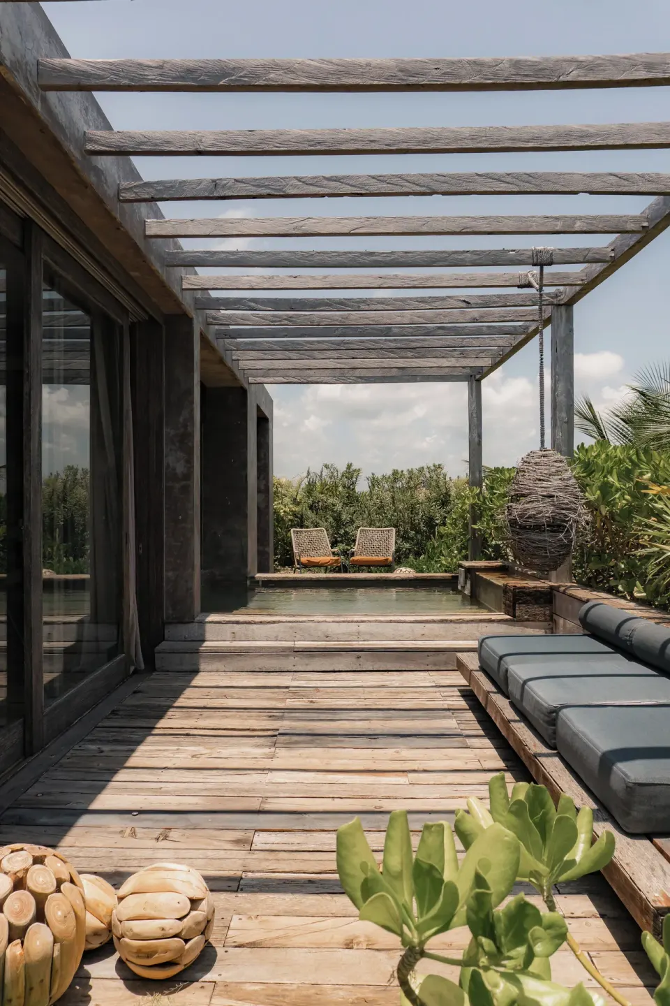 Private wood deck with loungers and shaded pergola at Nômade Temple Tulum