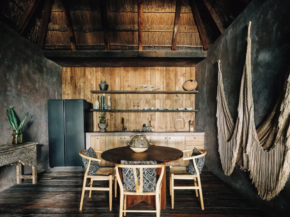 Dining table and woven hammocks inside a rustic suite at Nômade Temple Tulum