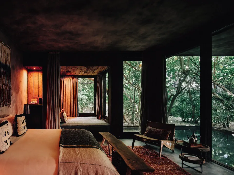 Suite interior with king bed, floor-to-ceiling windows and private pool at Nômade Temple Tulum