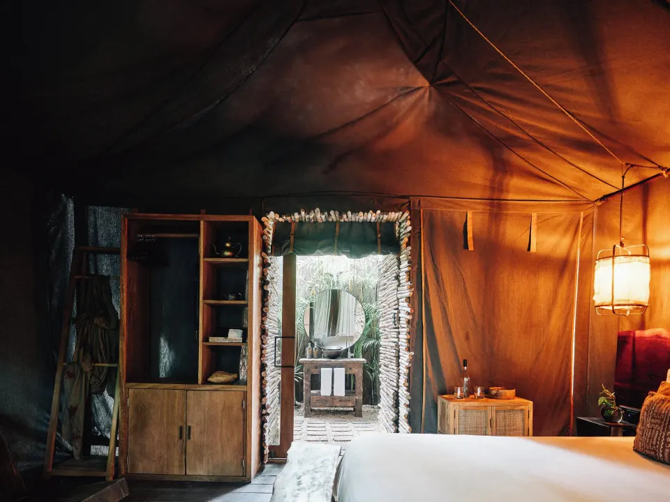 Tented bedroom interior with king bed and wooden storage at Nômade Temple Tulum