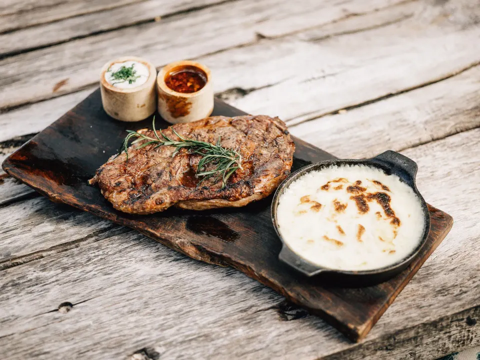 Grilled steak with dipping sauces on a wooden board at Nômade Temple Tulum