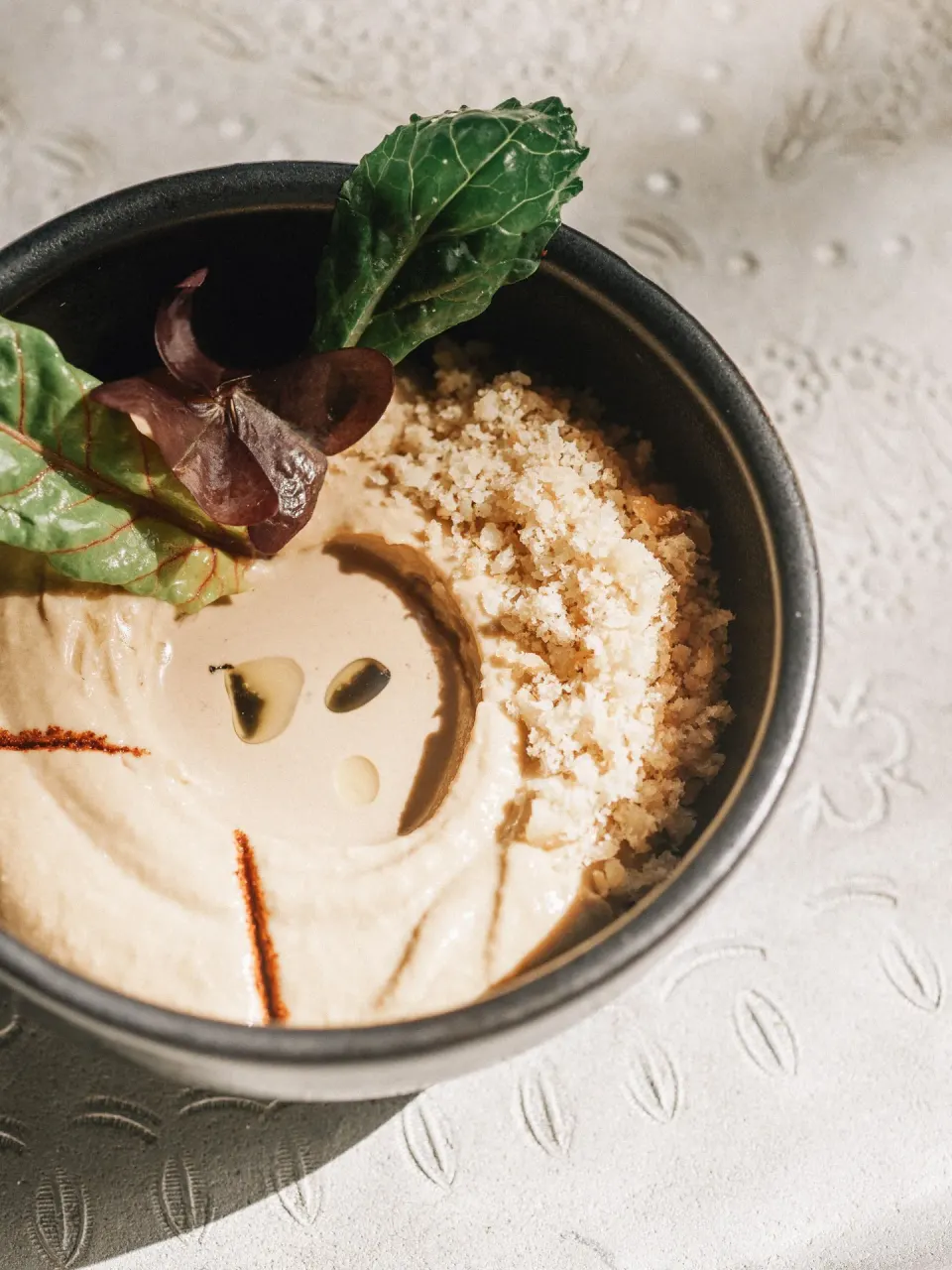 Bowl of whipped hummus with greens at Nômade Temple Tulum