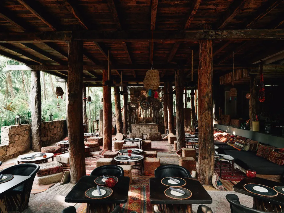 Shaded dining terrace with low tables, cushions and rugs at Nômade Temple Tulum.