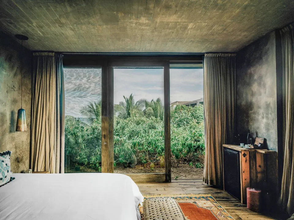 Deluxe Garden View room with king bed and sliding glass doors at Nômade Temple Tulum