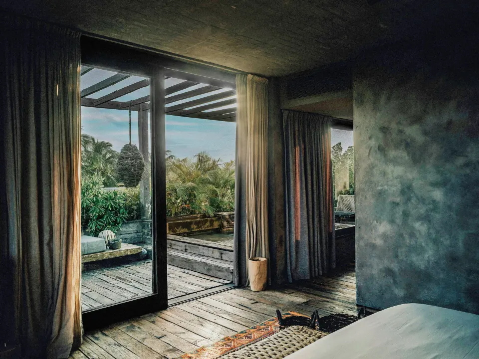 Interior view of Deluxe Garden View room showing bed, sliding doors and covered terrace at Nômade Temple Tulum