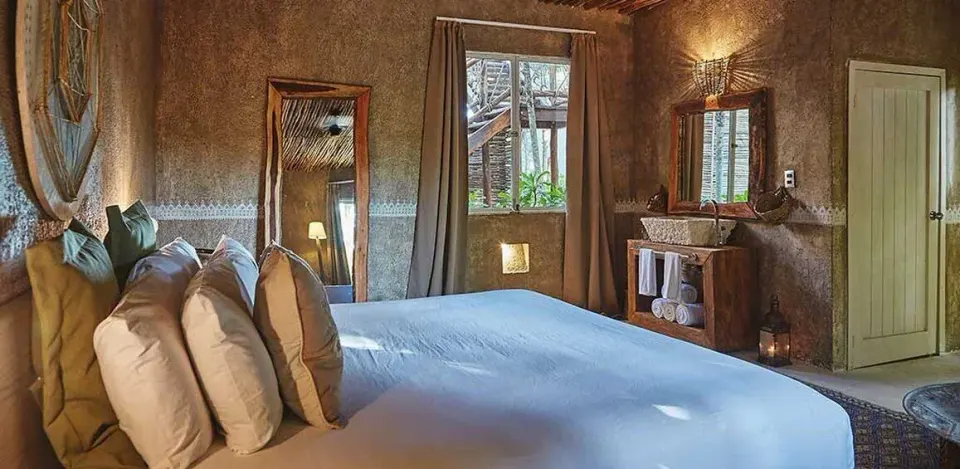 Deluxe Room Garden View king bed corner with mirror and vanity at Nômade Temple Tulum