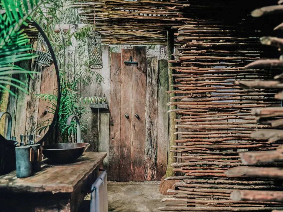 Deluxe Room garden-view bungalow rustic bathroom and outdoor shower at Nômade Temple Tulum