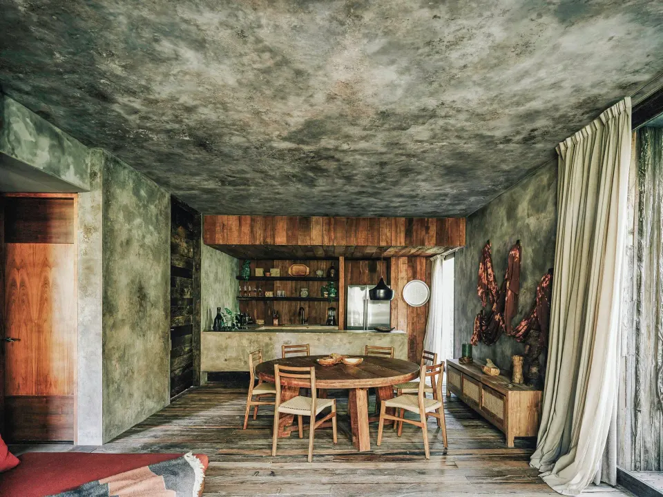 Open-plan living and dining area with round table and kitchenette in a Deluxe Room at Nômade Temple Tulum