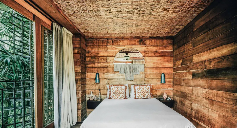 Deluxe Room Garden View treehouse bedroom headboard and mirror at Nômade Temple Tulum