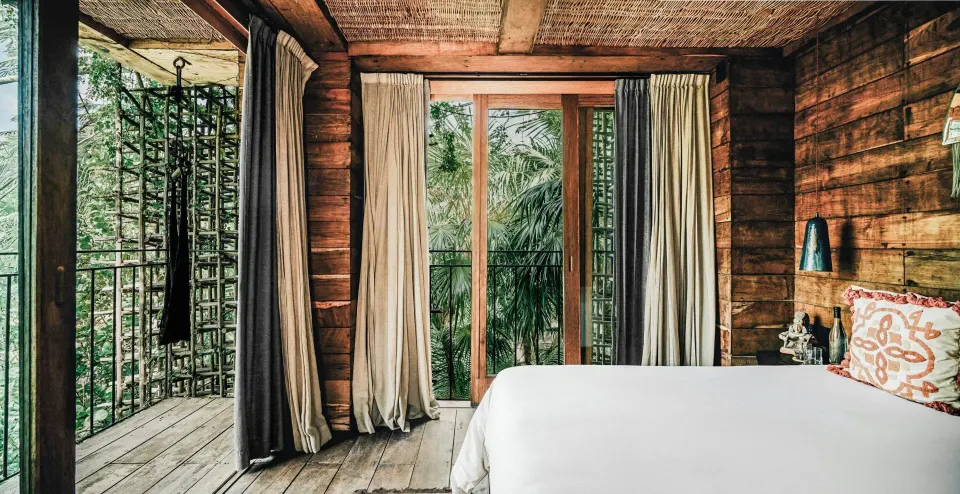 Deluxe Room Garden View treehouse bedroom with king bed at Nômade Temple Tulum