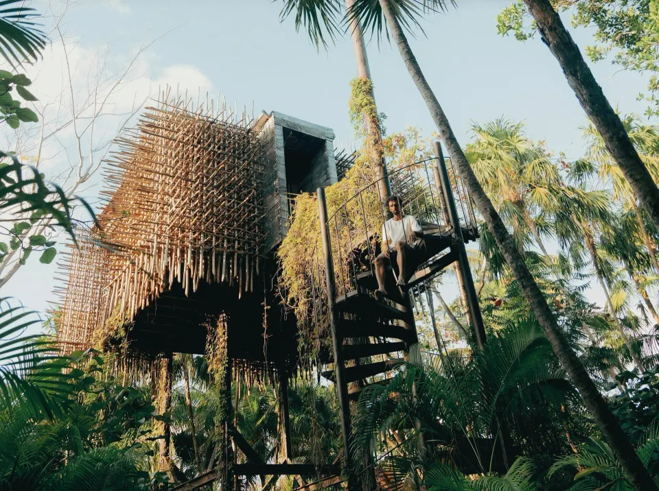 Elevated treehouse exterior with spiral staircase among trees at Nômade Temple Tulum