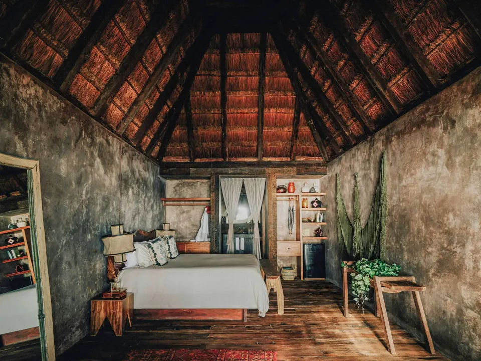 Deluxe guest room interior with king bed and palapa ceiling at Nômade Temple Tulum