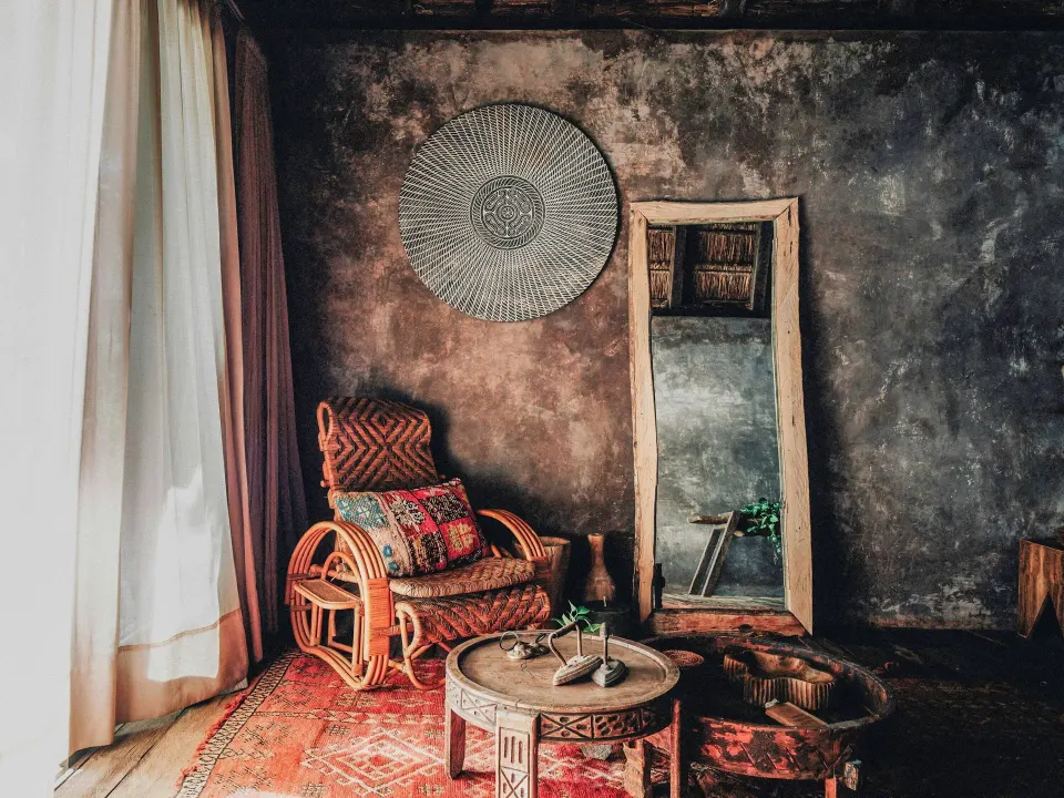 Seating nook with rattan chair and decorative mirror in a guest room at Nômade Temple Tulum