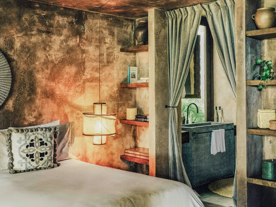King bed and doorway into the bathroom in a Deluxe Room at Nômade Temple Tulum