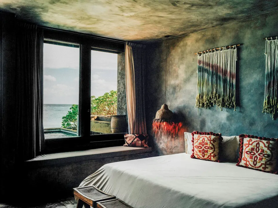 King bed and ocean view window in a Deluxe Room at Nômade Temple Tulum