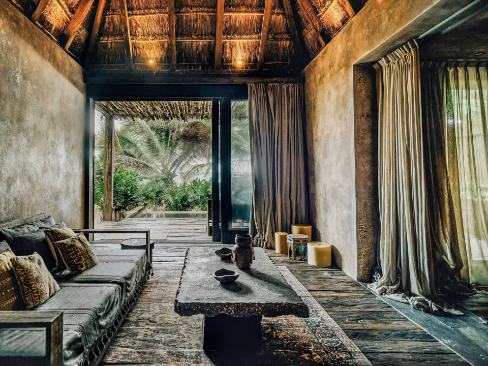 Lounge seating opening to a private deck and garden in a Deluxe Ocean View room at Nômade Temple Tulum