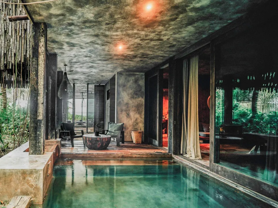 View along the plunge pool toward the covered terrace and room at Nômade Temple Tulum