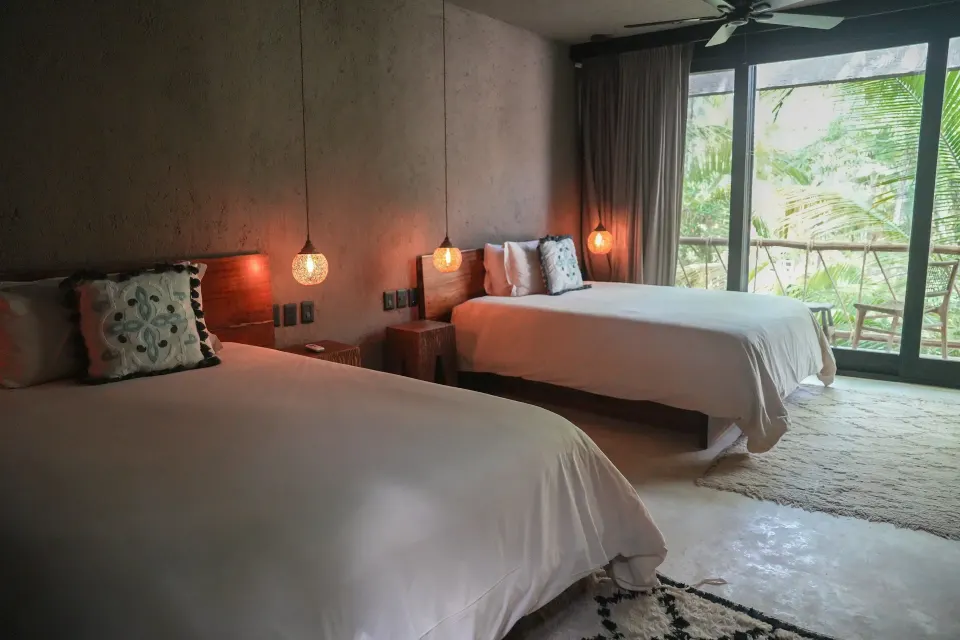 Deluxe guest room with two beds and hanging bedside lights at Nômade Temple Tulum