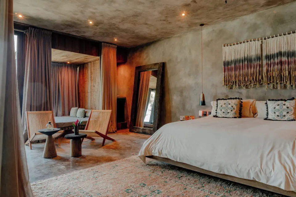 Spacious bedroom interior with king bed and seating in a Suite, Ocean View at Nômade Temple Tulum.
