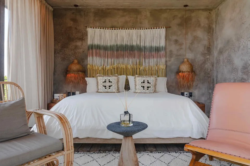 Front-facing king bed with woven headboard art in a Suite, Ocean View at Nômade Temple Tulum.