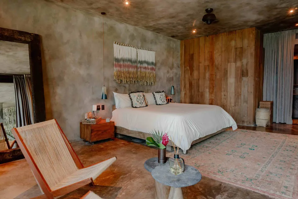 King bed and lounge chairs in a Suite, Ocean View at Nômade Temple Tulum.