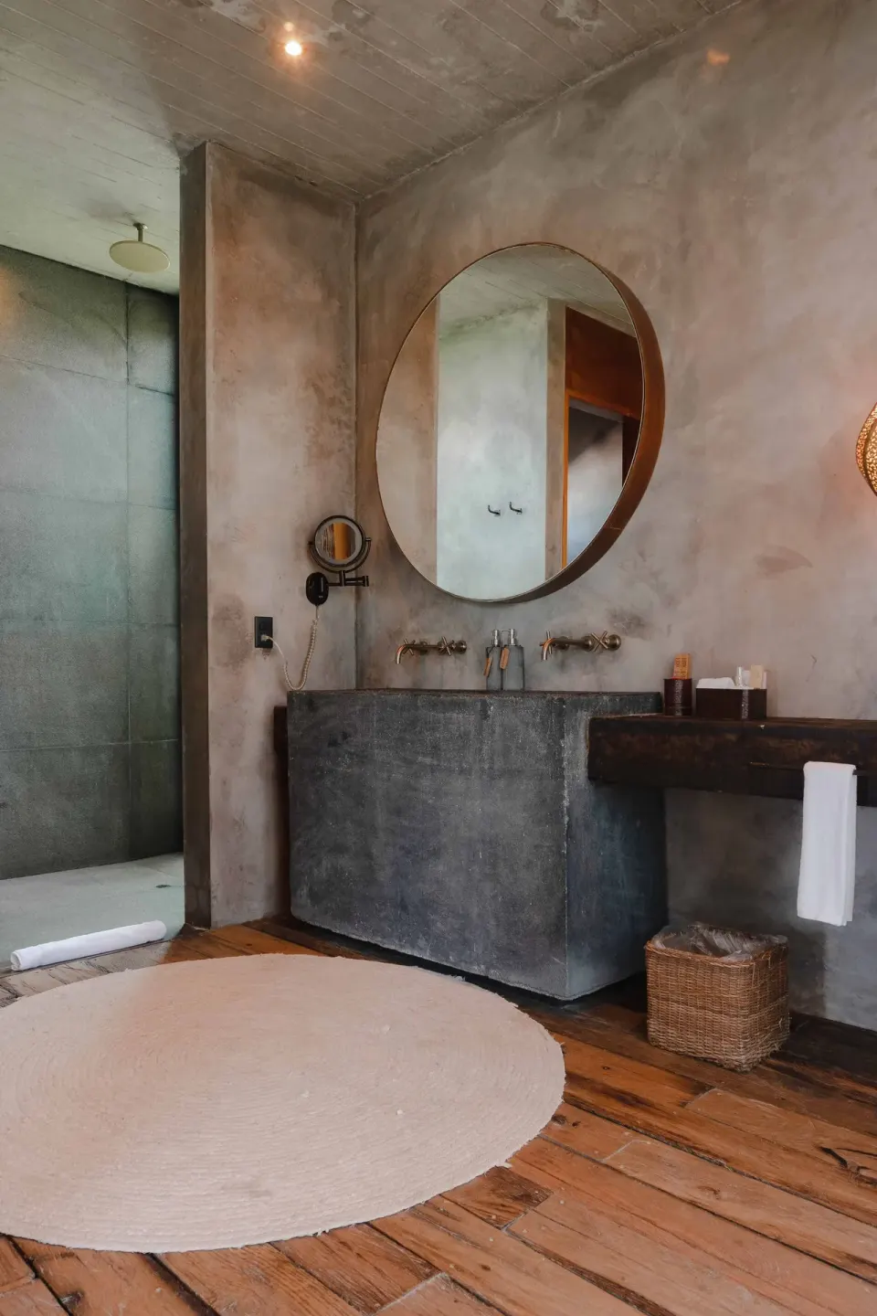 Concrete-finish bathroom vanity and round mirror in a Suite Ocean View at Nômade Temple Tulum.
