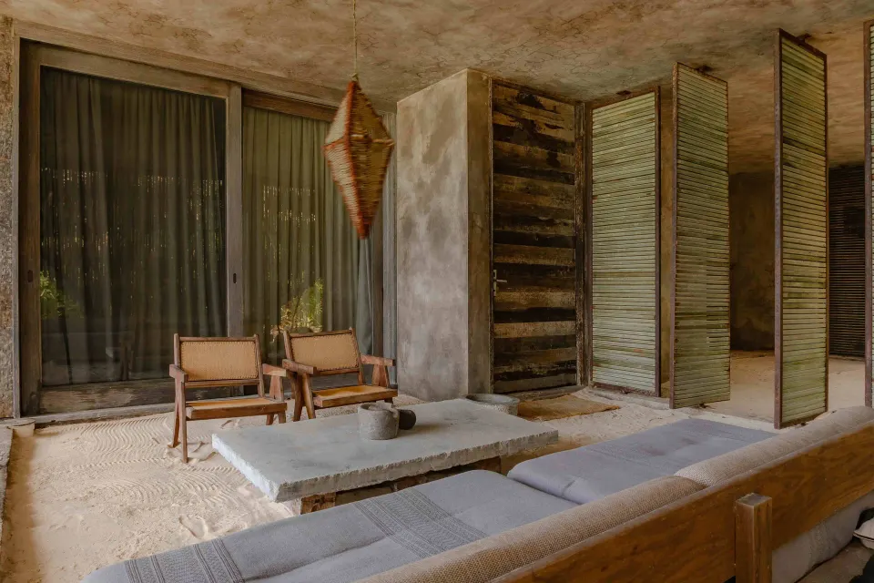 Living area with low sofa, stone coffee table and sliding doors in an Ocean View Suite at Nômade Temple Tulum.