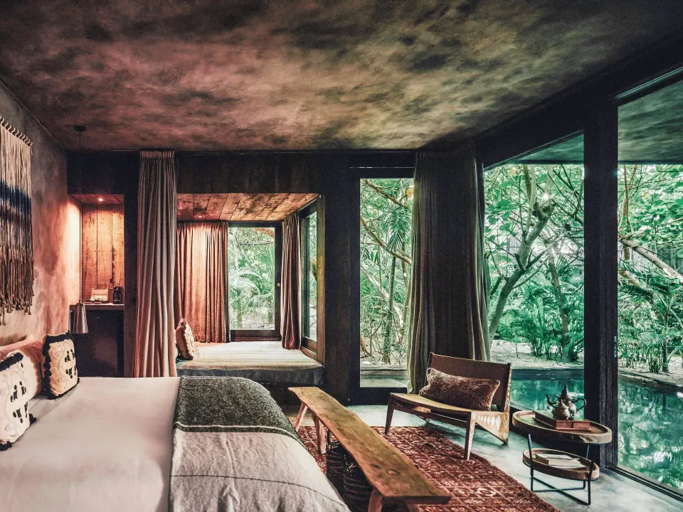 Junior suite king bed and seating area overlooking a plunge pool at Nômade Temple Tulum