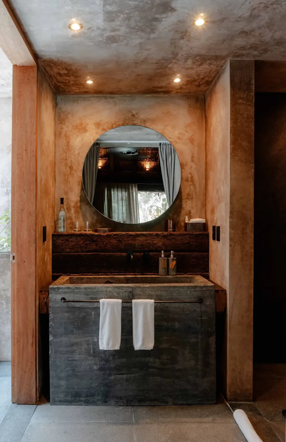 Bathroom vanity and round mirror in a Superior Room Beach View at Nômade Temple Tulum