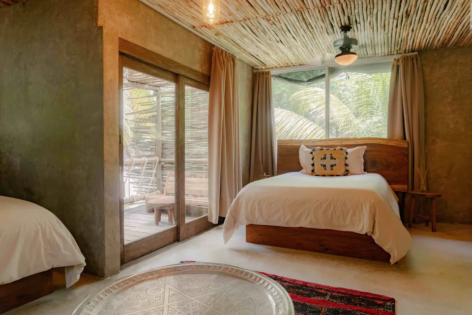 Bed and balcony view in a Superior Room Beach View at Nômade Temple Tulum with natural light
