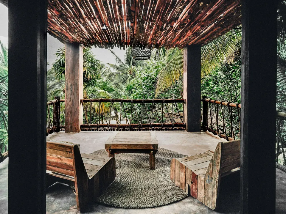 Shaded wooden terrace with seating and jungle views at a Superior Room Beach View at Nômade Temple Tulum
