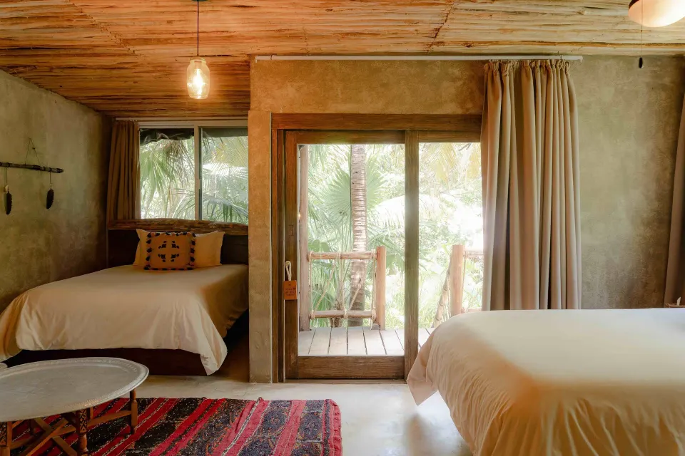 Interior view of Superior Room Beach View showing two beds and sliding doors to the balcony at Nômade Temple Tulum