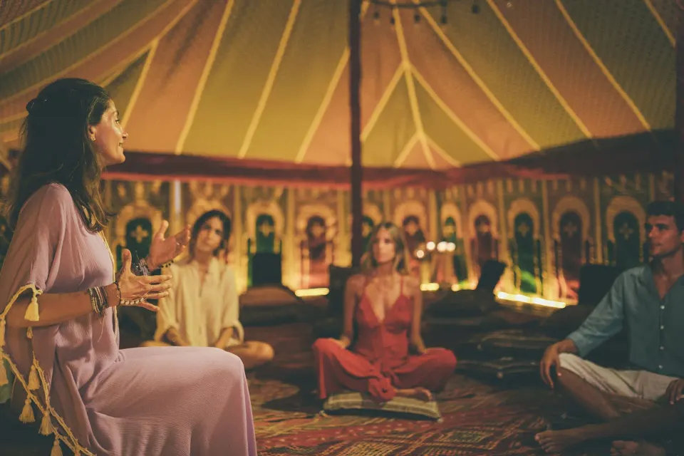 Small group seated in a dimly lit circular tent at Nômade Temple Tulum