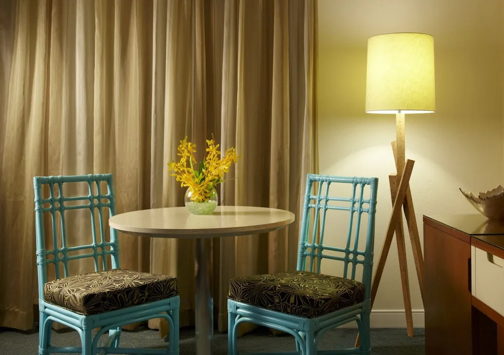 Guest room table with turquoise chairs and a floor lamp at Oasis Hotel Waikiki.