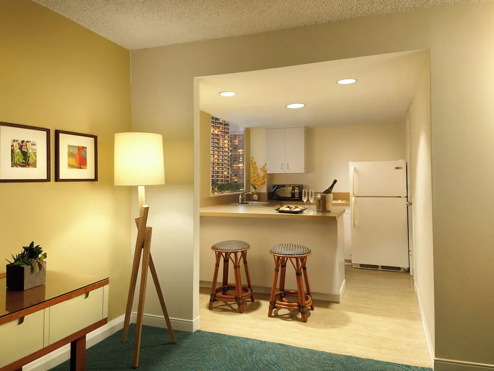 Guest room kitchenette with stools, refrigerator, and counter at Oasis Hotel Waikiki.