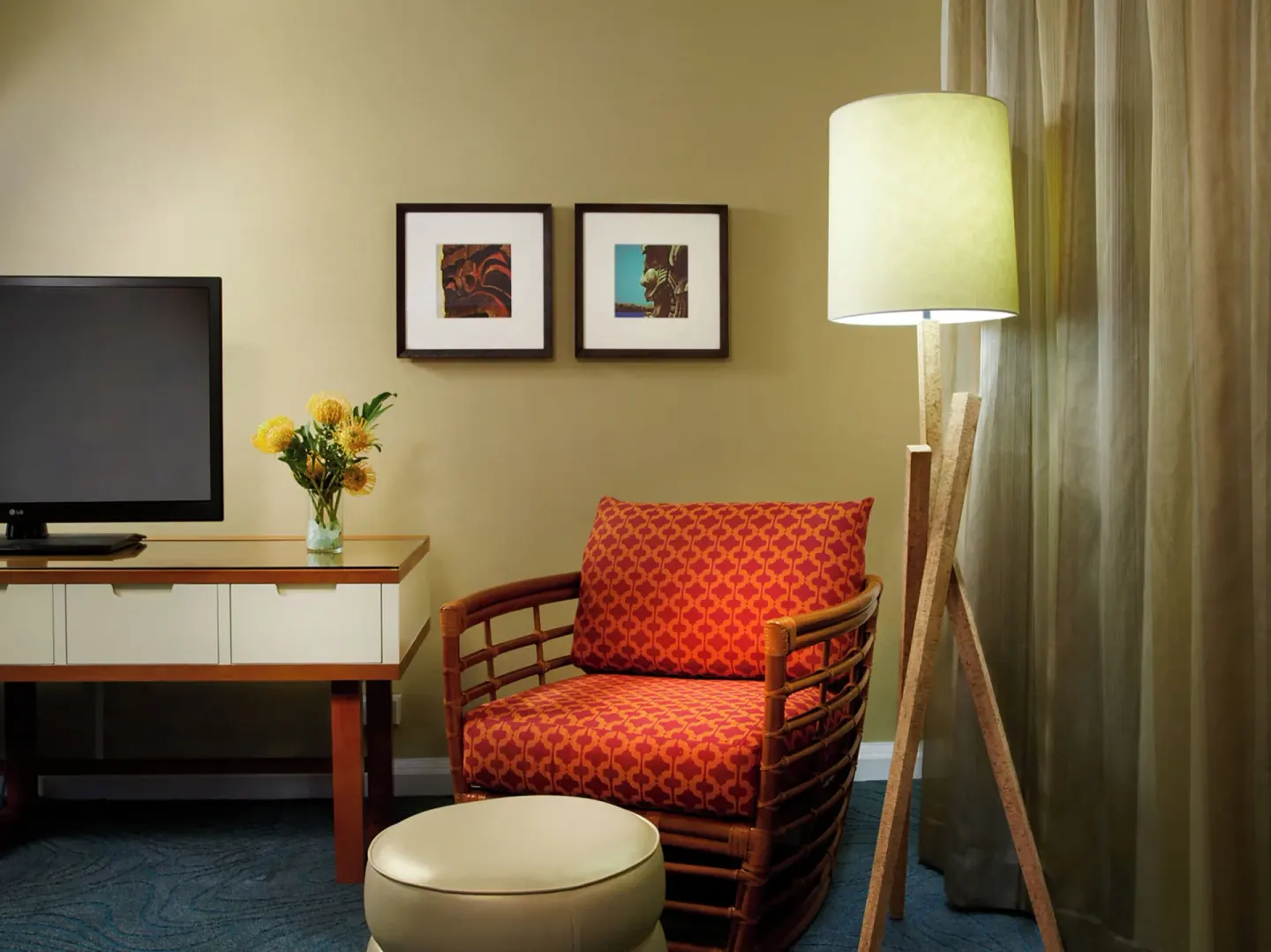 Guest room sitting area with patterned chair, TV, and floor lamp at Oasis Hotel Waikiki.