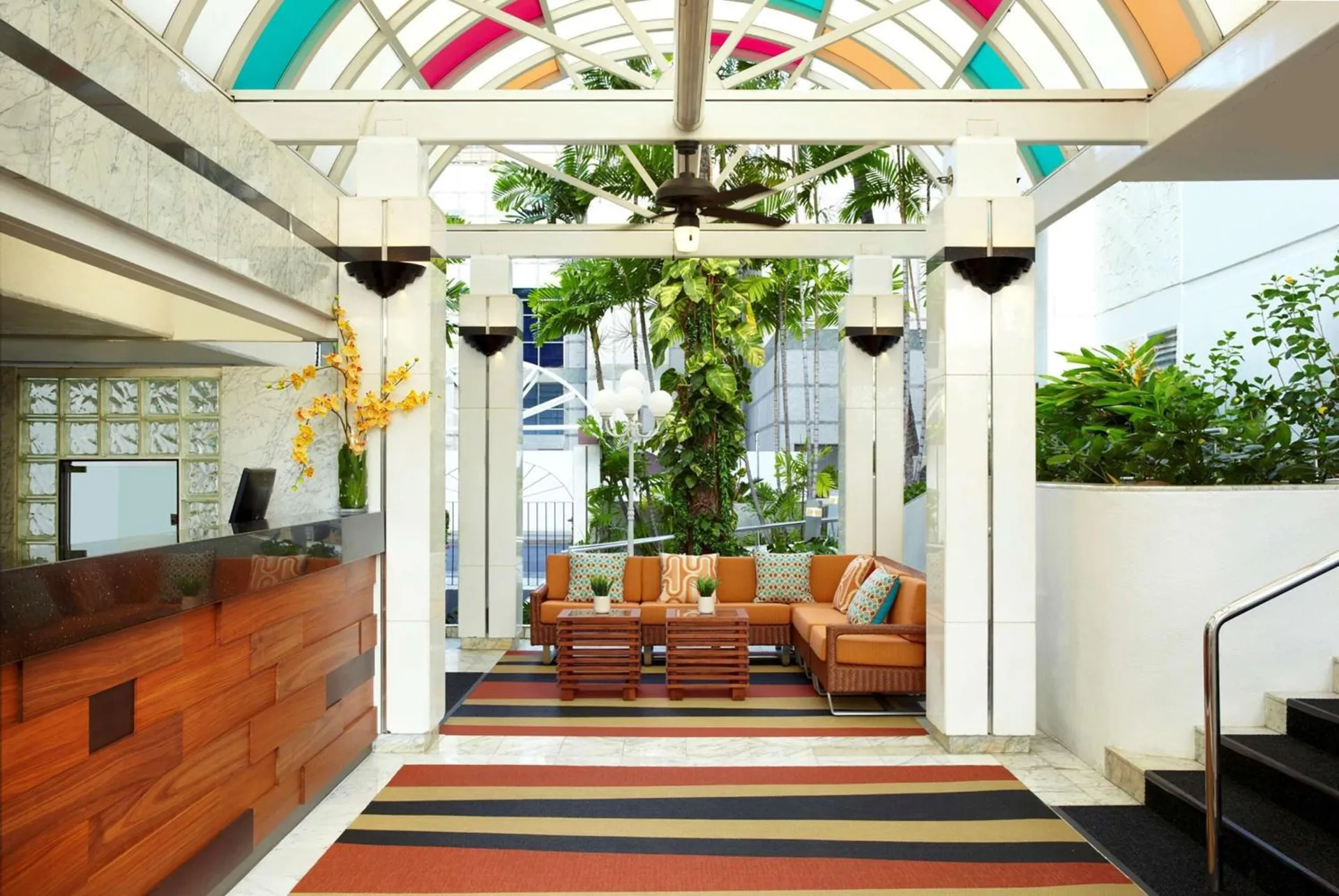 Lobby seating area with colorful skylight and reception desk at Oasis Hotel Waikiki.