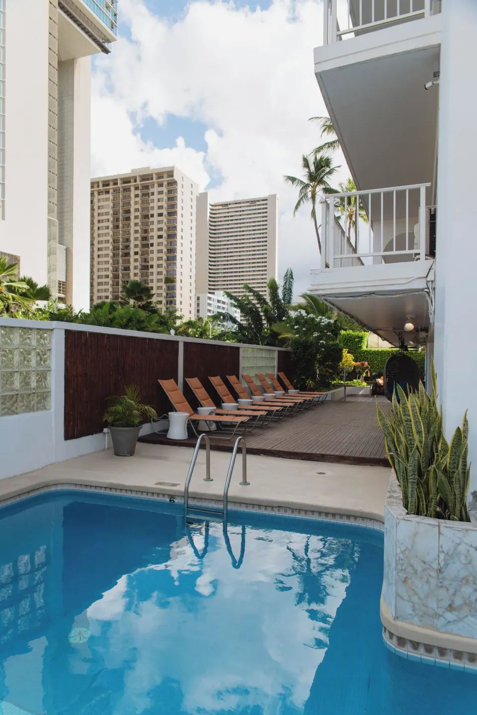 Outdoor pool with lounge chairs and surrounding balconies at Oasis Hotel Waikiki.