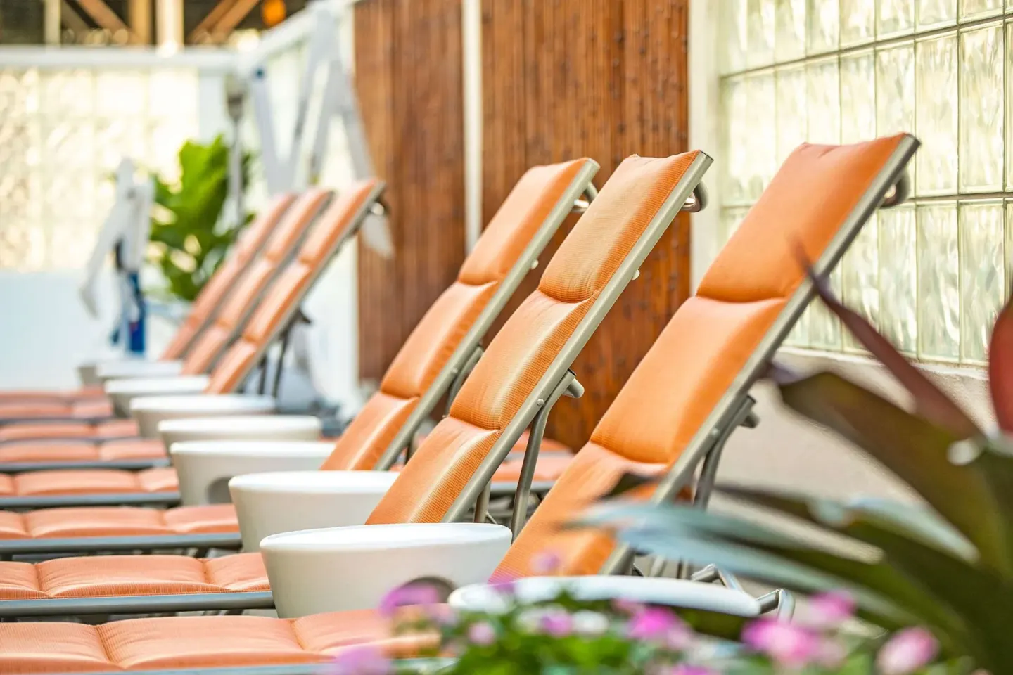 Orange cushioned pool loungers lined along a wall at Oasis Hotel Waikiki.