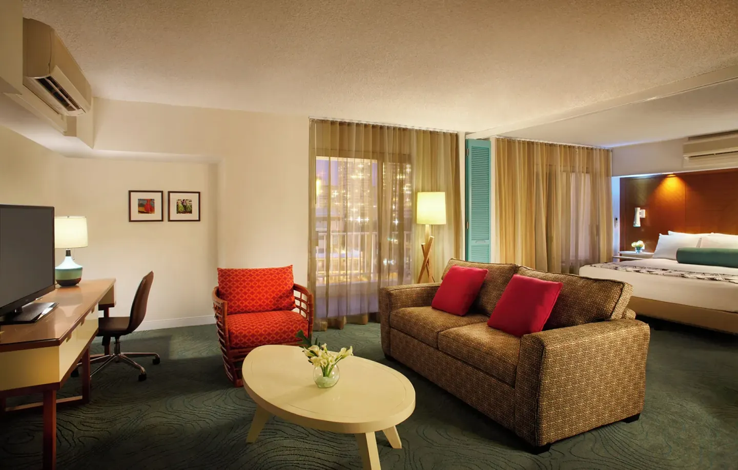 Suite with bed, sofa, desk, and lounge seating at Oasis Hotel Waikiki.