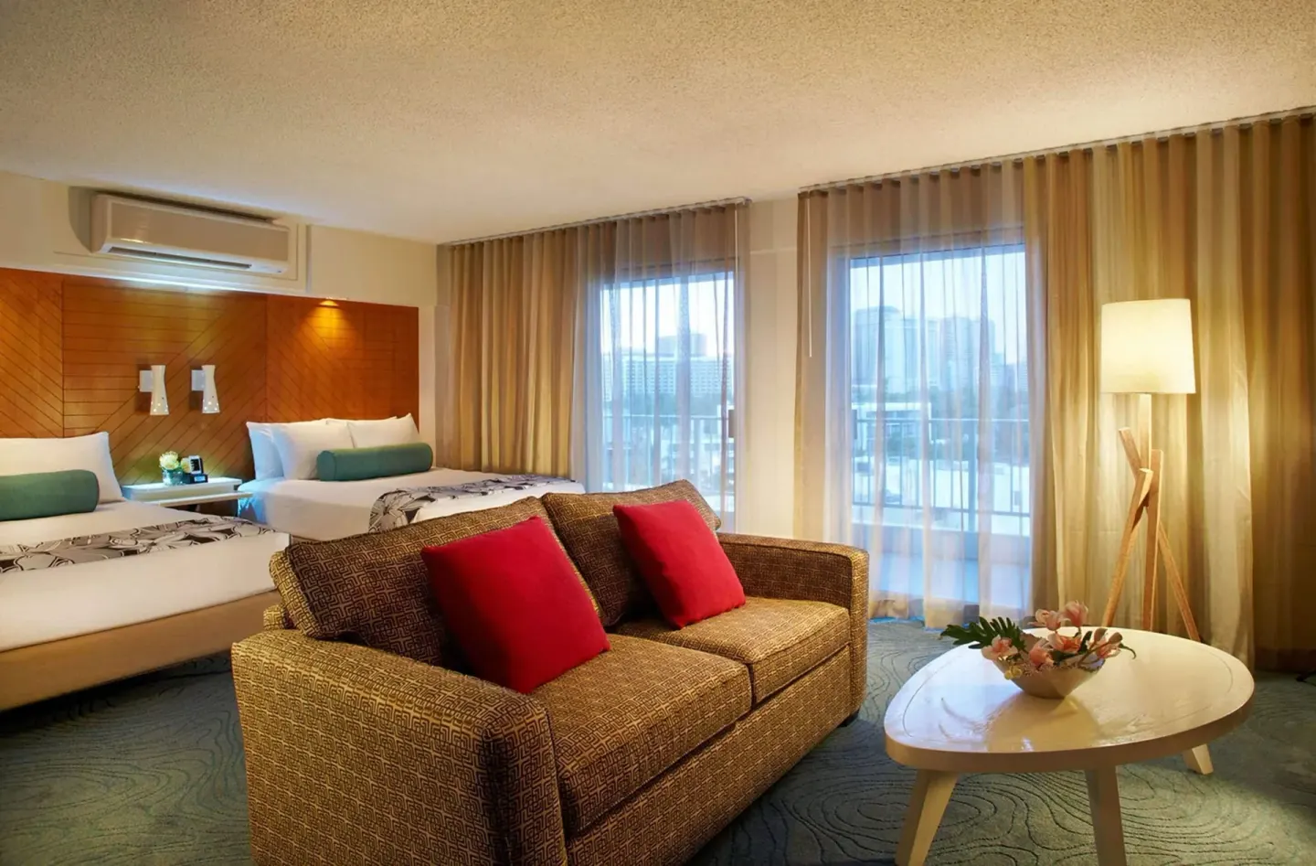 Junior Suite multiple beds with sofa and balcony doors at Oasis Hotel Waikiki.
