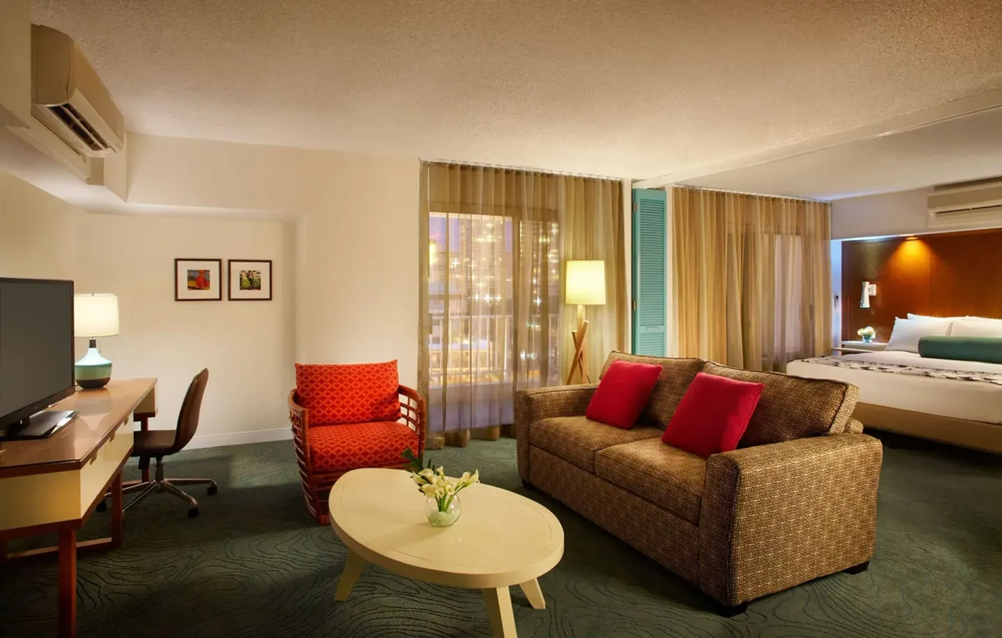 Junior suite sofa bed and bedroom area with desk at Oasis Hotel Waikiki.