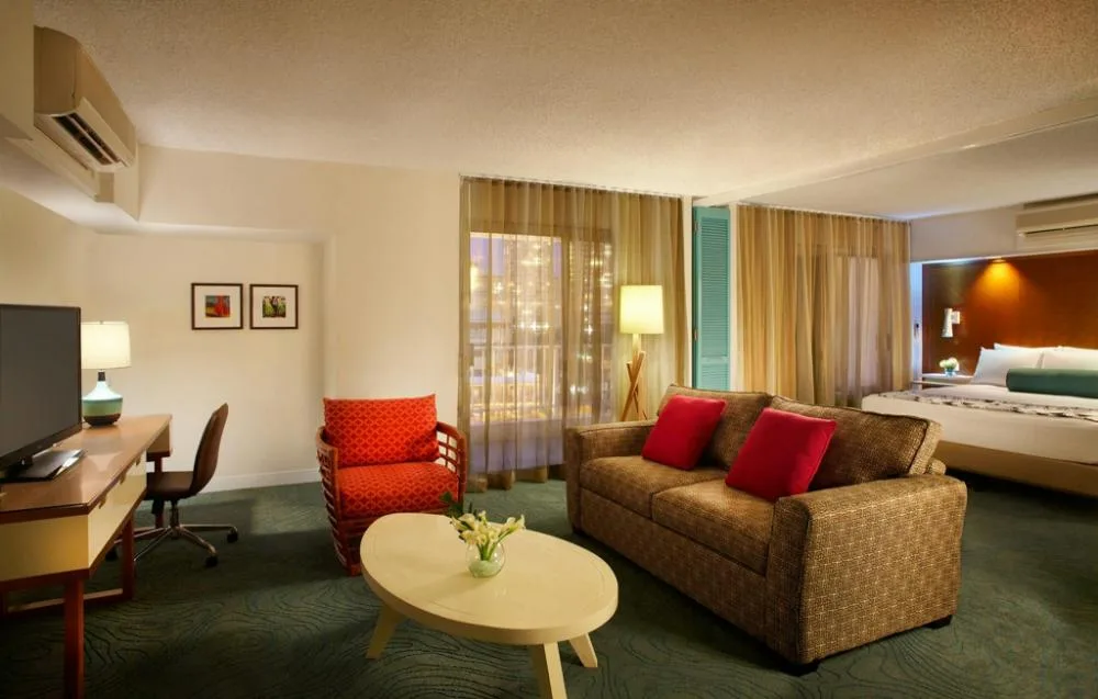 One Bedroom Executive Suite with sofa, desk, TV, and king bed at Oasis Hotel Waikiki.