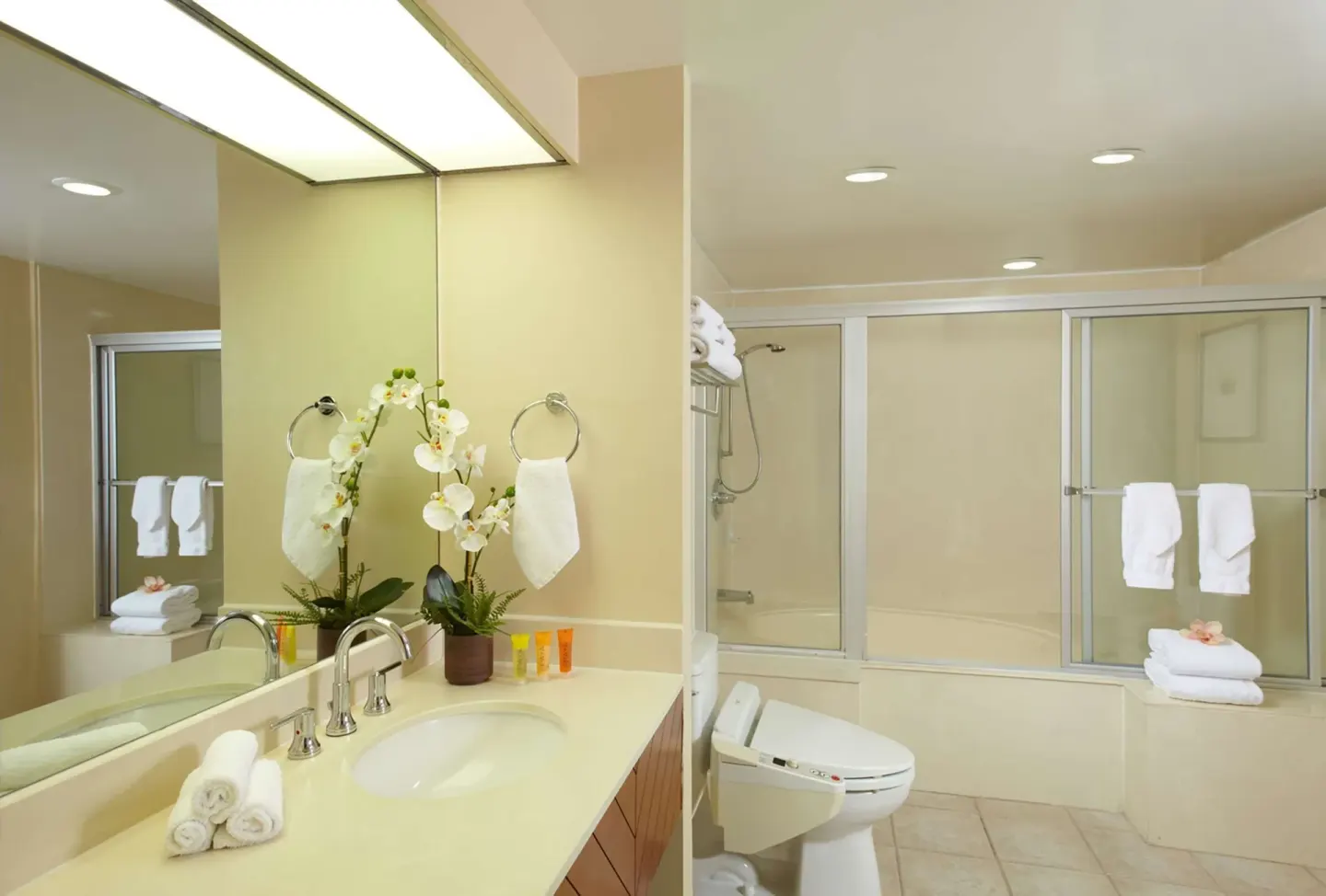 Standard Room bathroom with vanity, mirror, toilet and tub-shower at Oasis Hotel Waikiki.