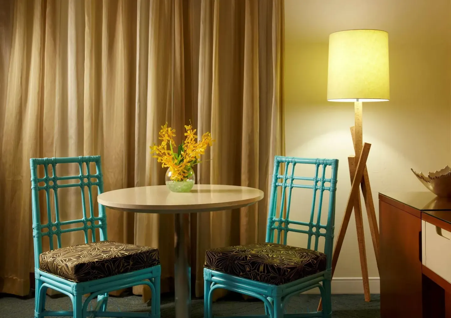 Standard Room table with turquoise chairs and floor lamp at Oasis Hotel Waikiki.
